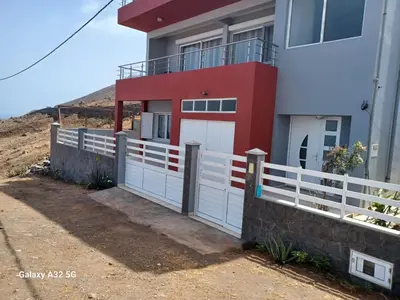 a red and white house with a white fence at Casa Larinha in Ponta do Sol