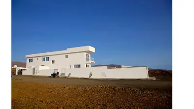 a white building in the middle of a field at Cacimba Sunset Lodge in Tarrafal