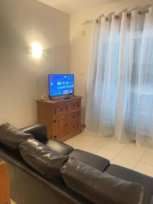 a living room with a leather couch and a television at Suíte Deluxe Soares in Prainha