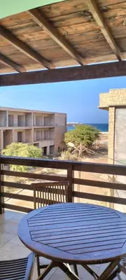 a blue table on a balcony with a view of the beach at Girasole Apartments in Sal Rei