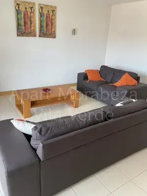 a living room with a black couch and a table at Morabeza Vila Verde in Santa Maria