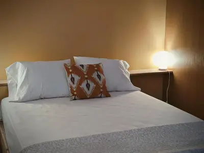 a bed with white pillows and a lamp on a wall at SeafrontView - Cozy T1 Apartment 2 in Praia