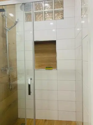 a white tiled bathroom with a shower with a window at Cantinho PeLe in Mindelo