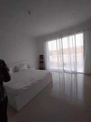 a white bedroom with a bed and a large window at Residencia Moreno in Praia