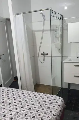 a bathroom with a shower and a bed and a sink at MeM Apartment in Praia