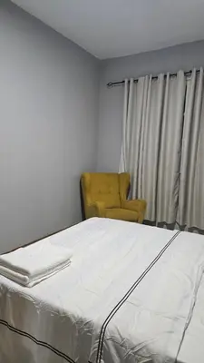 a bedroom with a bed and a yellow chair at Palmarejo Cozy Retreat in Praia