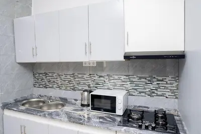 a kitchen with white cabinets and a sink and a microwave at J Martins Apart T11 Tarrafal in Tarrafal