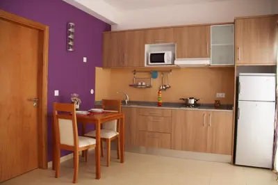 a kitchen with a table and a white refrigerator at Delfim Apartamentos in Praia