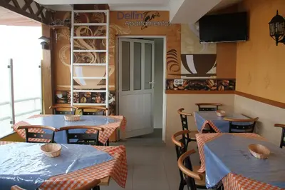 a restaurant with tables and chairs and a television at Delfim Apartamentos in Praia
