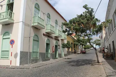 a street with a building with green windows and a tree at Djarfogo house in São Filipe