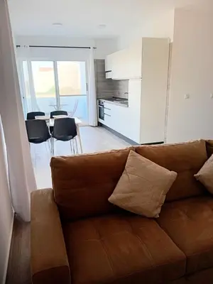 a living room with a brown couch and a kitchen at Appartamenti Praia Estoril, Sal Rei, Boa Vista in Sal Rei
