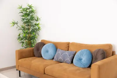a brown couch with two blue pillows on it at Marel Bliss Apartments T2 Camila in Mindelo