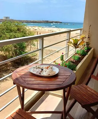a plate of food on a table on a balcony with the beach at Onda do Mar in Sal Rei