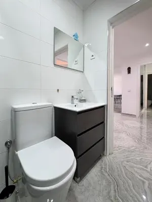 a white bathroom with a toilet and a sink at Spacious 3-bdr apartment - Palmarejo Grande - LCGR in Praia