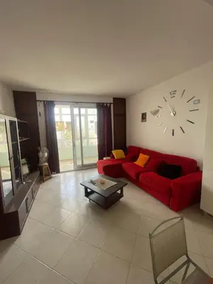 a living room with a red couch and a clock on the wall at Two Bedroom Apt - 150 meters from the Beach in Santa Maria