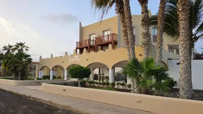 a yellow building with palm trees in front of it at T&C No Stress apartment in Santa Maria