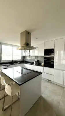a kitchen with white cabinets and a black counter top at Laginha Paradise III in Mindelo