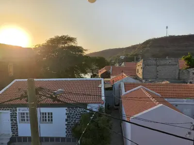 a view of the roofs of houses with the sunset at Ocean view Apartment 2 in Cidade Velha