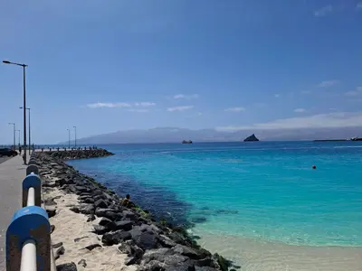 a beach with blue water and a pier at R3 Apartments - Laginha in Mindelo