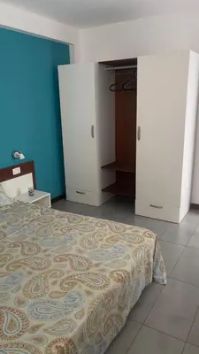 a bedroom with a bed and a blue wall at Apartamento T1 - Hotel Las Rochas in Mindelo