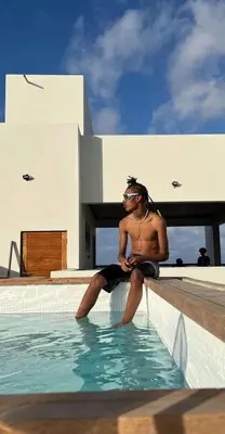 a man sitting on the edge of a swimming pool at Boutique Hotel Luz da Lua in Ponta do Sol