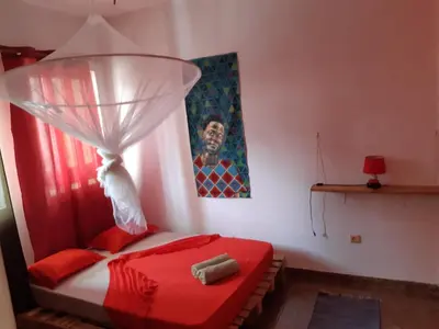 a bedroom with a red bed with a red canopy at Kasa Sirena in Tarrafal