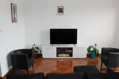 a living room with a flat screen tv and chairs at La Kaza du Soleil in Tarrafal