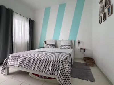 a bedroom with a bed with a striped wall at Appartement moderne au paradis in Santa Maria