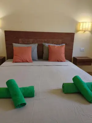 a large bed with two green pillows on it at Marialva Tropical T2 in Santa Maria