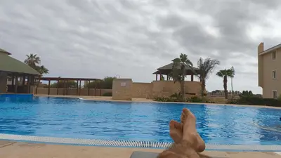 a man laying on the edge of a swimming pool at Marialva Tropical T2 in Santa Maria