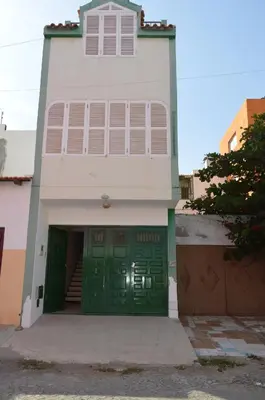 a white house with a green garage door at Apartamentos Sossego in Praia