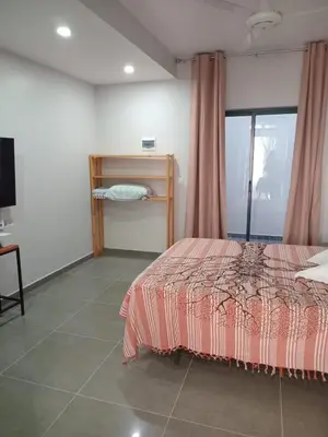 a bedroom with a bed and a table and a window at Abraço d Mindel in Mindelo
