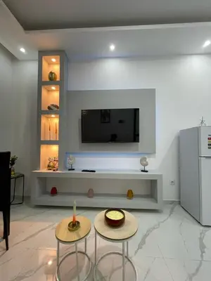 a living room with two tables and a tv on a wall at Di Rosa Apartament in Praia