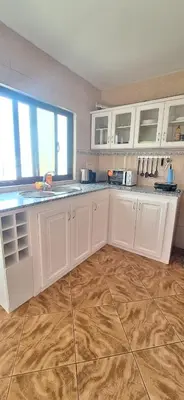 a kitchen with white cabinets and a wooden floor at Morabeza Serena in Santa Maria