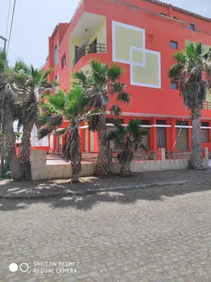 a red building with palm trees in front of it at Morabeza Serena in Santa Maria