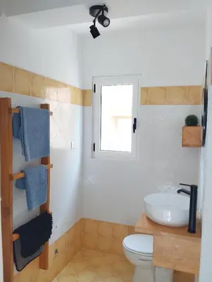 a bathroom with a toilet and a sink and a window at Kite Sal in Santa Maria