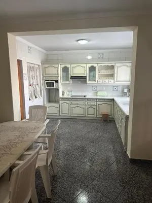 a kitchen with white cabinets and a table and chairs at Appartement avec Vue sur Mer à Praia, Wi-Fi, Navette Aéroport avec supplément in Praia