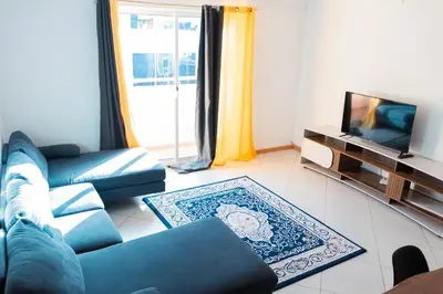 a living room with a couch and a tv at Palmarejo, Apartamento T2 no Prédio Rosa Trás de pão quente in Praia