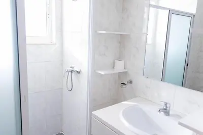 a white bathroom with a sink and a shower at Palmarejo, Apartamento T2 no Prédio Rosa Trás de pão quente in Praia