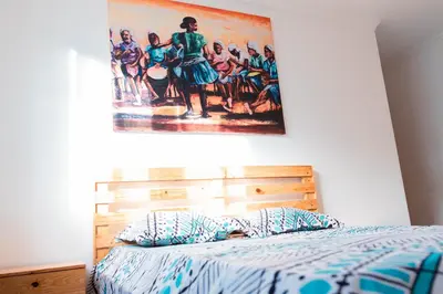 a bedroom with a bed with a painting on the wall at Palmarejo, Apartamento T2 no Prédio Rosa Trás de pão quente in Praia