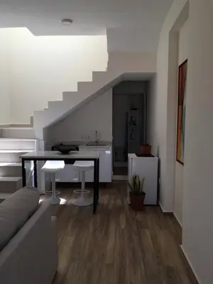 a living room with a table and a staircase at Alana's loft in Praia