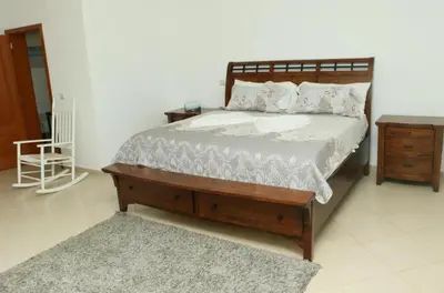 a bedroom with a bed with a wooden frame and a table at Cidade Serena in Cidade Velha
