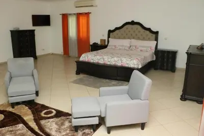 a bedroom with a bed and two chairs at Cidade Serena in Cidade Velha