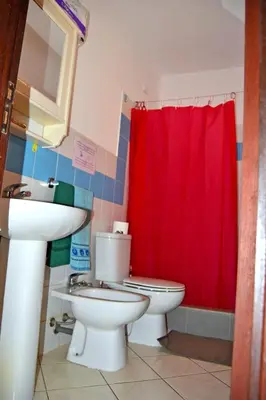 a bathroom with a toilet and a sink and a red shower curtain at Central Apartamento Fogo 101 in Santa Maria
