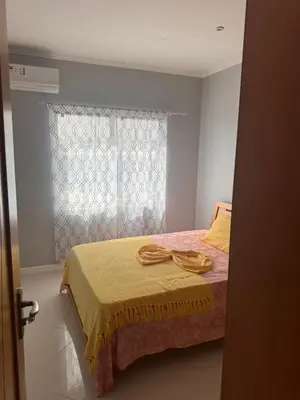 a bedroom with a bed with a yellow blanket and a window at Apartamento mais Carro George Mendes in Praia