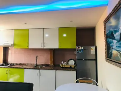 a kitchen with green and white cabinets and a refrigerator at PJ t1 conforto e paz 4E in Praia