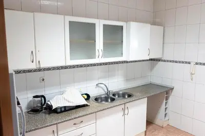 a kitchen with white cabinets and a sink at Palmarejo, Apartamento T1, frente Praça Center in Praia