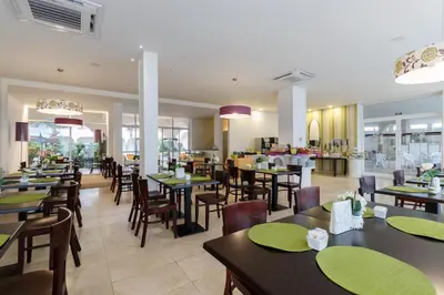 a restaurant with tables and chairs and a cafeteria at Ouril Pontao Hotel in Santa Maria