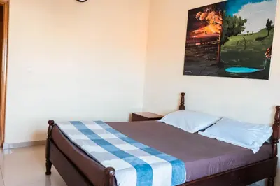 a bed in a room with a painting on the wall at Apartamento T1 em Palmarejo, Trás de pão quente in Praia
