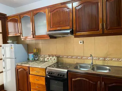 a kitchen with wooden cabinets and a sink and a refrigerator at Apartamento em Monte in Mindelo